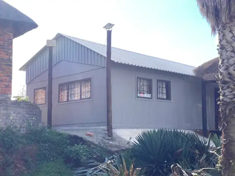 Contemporary house with metal siding, solar-powered outdoor lighting, and lush landscaping.